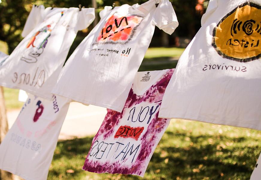 T-shirts hanging on a clothes line in front of the library with messages raising awareness to gender-based violence